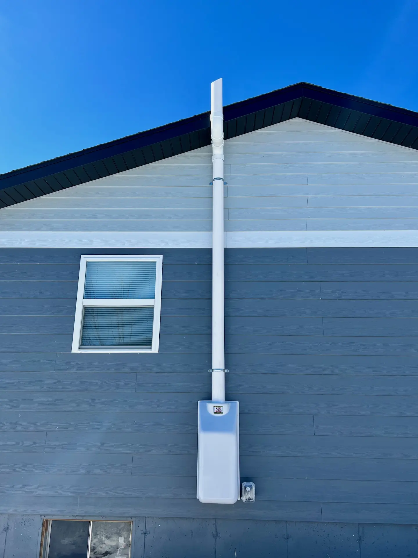 Exterior radon mitigation system installed on a home in Rapid City, South Dakota.